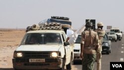 Seorang laki-laki nampak sedang melambaikan bendera putih kepada petugas yang akan memeriksa kendaraan dan muatannya di pos-pos penjagaan menuju Sirte, Libya (28/8).