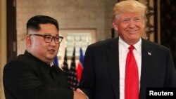 Pemimpin Korut Kim Jong Un (kiri) dan Presiden AS Donald Trump dalam KTT Pertama di Singapura, 12 Juni 2018. 