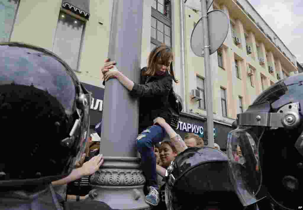 A protestor is pulled down from a lamp post during a demonstration in downtown Moscow, Russia, Monday, June 12, 2017.