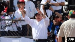 El presidente nicaragüense, Daniel Ortega (C), muestra el signo V mientras saluda a sus simpatizantes durante la conmemoración del 40 aniversario de la Revolución Sandinista en la plaza "La Fe" en Managua.