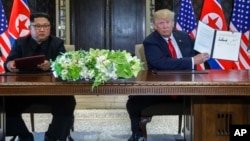 U.S. President Donald Trump holds up the document that he and North Korea leader Kim Jong Un had signed at the Capella resort on Sentosa Island, June 12, 2018, in Singapore. 