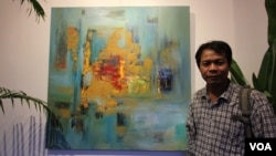 លោក ឈឹម​ សុធី​ ជា​វិចិត្រករ​ដ៏​មាន​បទ​ពិសោធ​យូរ​ឆ្នាំ​ ឈរ​នៅ​មុខ​គំនូរ​របស់​លោក​ ដែល​ត្រូវ​បាន​ដាក់​បង្ហាញ​ក្នុង​ពិព័រណ៌​ «Consuming Passion»​ ក្នុង​​សណ្ឋាគារ​ ក្នុង​រាជធានី​ភ្នំពេញ​ កាល​ពី​ថ្ងៃ​ទី​២៥​ ខែ​មិថុនា​ ឆ្នាំ​២០១៥។​ ពិព័រណ៌​គំនូរ​នេះ​អំពាវនាវ​ឲ្យ​មាន​ការថែរក្សា​បរិស្ថាន​និង​ធនធាន​ធម្មជាតិ​នៅ​ក្នុង​ប្រទេស​កម្ពុជា​ (នូវ​ ពៅ​លក្ខិណា/VOA)