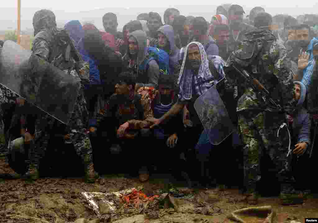 Macedonian policemen try to keep migrants and refugees under control before they cross the border line from Greece into Macedonia, near the Greek village of Idomeni. Most of the people flooding into Europe are fleeing violence and persecution in their home countries and have a legal right to seek asylum, the United Nations said.