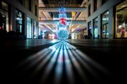 Un hombre de nieve iluminado a la entrada de un vacío Mall de Berlín, el miércoles 16 de diciembre de 2020 por la noche en la capital alemana, cuando el país entró a un cierre más restrictivo por el COVID-19.
