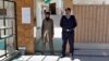 A Pakistani police officer stands guard with a worker of a religious group at the entrance to a mosque in Islamabad, Pakistan, March 6, 2019.
