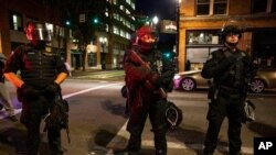 Policías de armados con fusiles de guerra mantienen la vigilancia en Portland, Oregon, durante protestas en agosto.