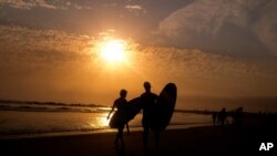 资料照片：加利福尼亚州洛杉矶威尼斯海滩夕阳下的冲浪者。(2021年6月16日)