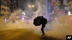 资料照片：2020年元月1日，香港一名抗议者在警方施放催泪弹时撑着雨伞。