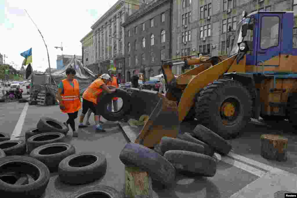 Municipal workers remove tires as they dismantle barricades set up during the protests that toppled Moscow-backed president Viktor Yanukovych in central Kyiv, July 1, 2014.