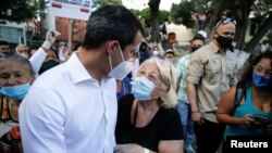 El político venezolano y líder opositor Juan Guaidó, a la izquierda, saluda a sus partidarios durante una consulta organizada por la oposición. Diciembre 12, 2020.