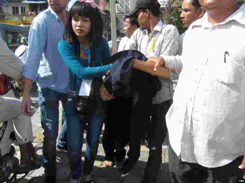 Opposition activists and human rights officials protect a security guard from being attacked by angry protesters, Phnom Penh, Cambodia, July 15, 2014. (Khoun Theara/VOA)
