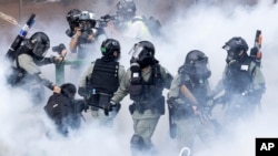 Police in riot gear move through a cloud of smoke as they detain a protester at the Hong Kong Polytechnic University in Hong Kong, Monday, Nov. 18, 2019. (AP Photo/Ng Han Guan)