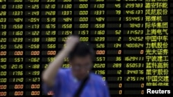 Investor berdiri di depan papan elektronik berisi informasi saham di sebuah pialang saham di Shanghai, China (24/8). (Reuters/Aly Song)