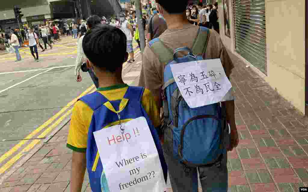 40多歲的香港市民王女士帶同10歲的兒子上街,他們在背包上貼上標語。(美國之音湯惠芸拍攝)
