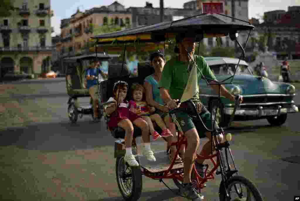 A woman with two girls travel in a rickshaw through the center of Havana, Cuba, Jan. 19, 2015. Cuba has so far offered a guardedly positive reception to President Barack Obama's loosening of the trade embargo on Cuba, saying it welcomes the full package of new economic ties on offer, but it insists it will maintain its one-party political system and centrally planned economy.