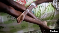 FILE - A boy rests his arm on his mother's legs as he receives treatment for cholera after Hurricane Matthew in the Hospital of Les Anglais, Haiti, Oct. 10, 2016.