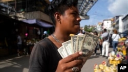 Un joven muestra sus billetes de un dólar en un mercado callejero en Caracas, el 11 de junio de 2021. Foto: AP.