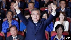 South Korea's presidential candidate Moon Jae-in of the Democratic Party raises his hands as his party leaders and members watch on television local media's results of exit polls for the presidential election in Seoul, South Korea, May 9, 2017. 
