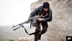 FILE - In this December 17, 2012 file photo, a Free Syrian Army fighter takes cover during fighting with the Syrian Army in Azaz, Syria.