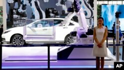 FILE - An industrial robot is displayed with a car at the booth of a Chinese automaker during the China Auto 2018 show in Beijing, China, Apr. 26, 2018.