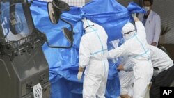 日本自衛隊員星期五在福島核電站把踏入受核污染的水中的工人轉移