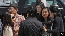 Students and onlookers at Oikos University talk amongst themselves at the scene of a multiple shooting at the school in Oakland, California, April 2, 2012. 