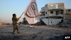 Pemberontak Suriah yang didukung Turki memegang bendera divisinya di kota perbatasan barat laut al-Bab setelah mereka sepenuhnya merebut kota tersebut dari militan ISIS, 23 Februari 2017 (AFP PHOTO / Nazeer al-Khatib).