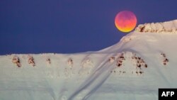 A super blue blood moon behind a mountain is seen from Longyearbyen, Svalbard, Norway, Jan. 31, 2018.