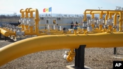 FILE - Men stand next to pipelines of the national natural gas distribution network outside Ungheni, Moldova, March 4, 2015.