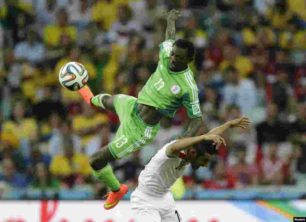 Nigeria's Juwon Oshaniwa (L) jumps for the ball with Iran's Reza Ghoochannejhad during their 2014 World Cup Group F soccer match at the Baixada arena in Curitiba, June 16, 2014.