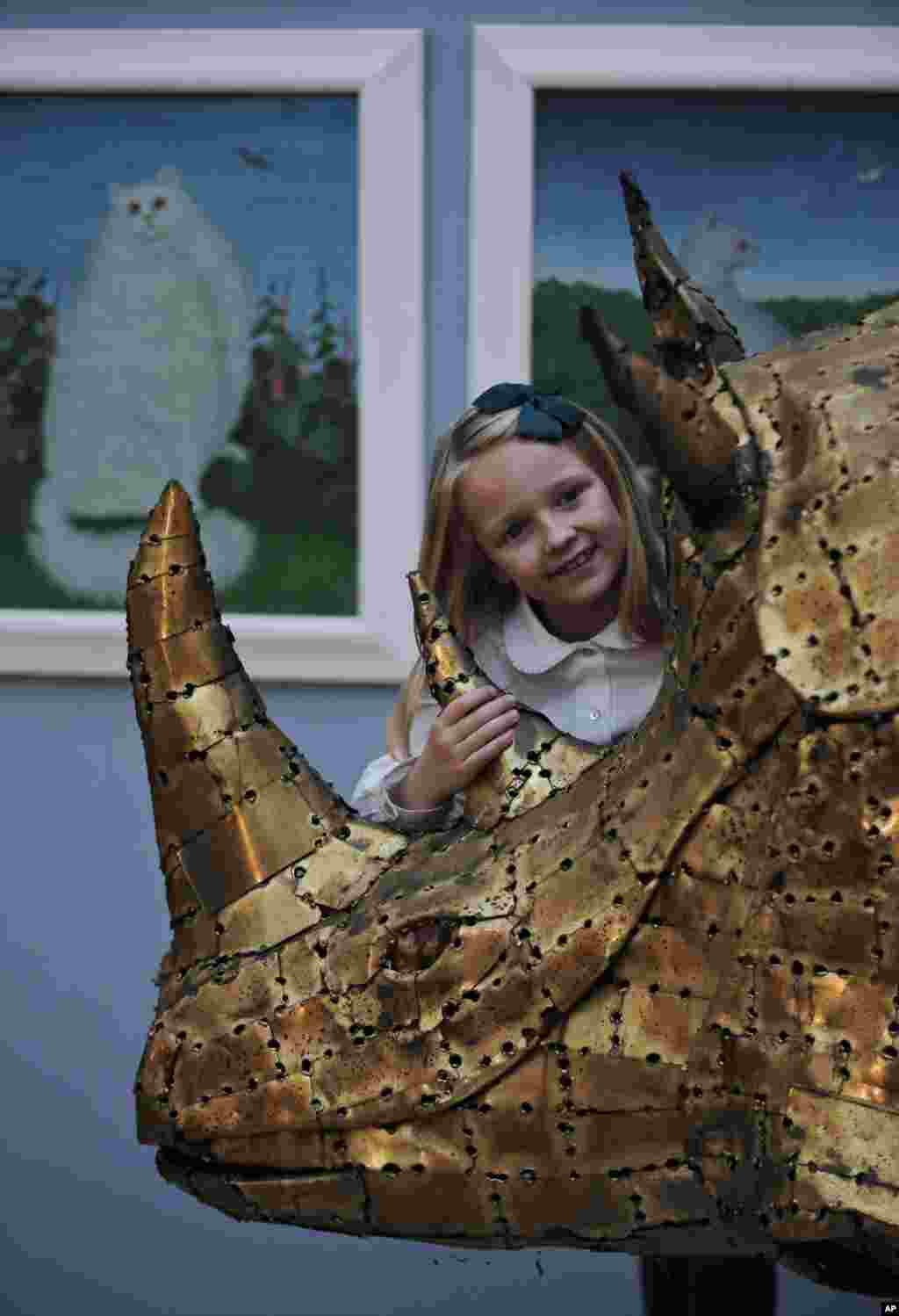 Une fille caresse une sculpture de bronze représentant un rhinocéros lors d'une vente aux enchères sur le thème que propose l'animal dans l'inspiration artistique de presse, intitulé les «créatures grandes et petites, à Londres, le lundi 15 décembre 2014