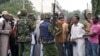 Kenyan policemen watch over youths protesting against the killing of Sheikh Aboud Rogo Mohammed, Mombasa, August 31, 2012. 