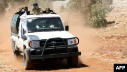 Pejuang Suriah berdiri di bagian belakang truk pick up saat berpartisipasi dalam latihan perang untuk mengantisipasi serangan rezim di Provinsi Idlib dan di sekitar daerah pedesaan. Latihan ini diadakan sebagai bagian acara kelulusan anggota Hayat Tahrir al-Sham (HTS) di sebuah kamp di pedesaan di Provinsi Idlib, 24 Agustus 2018.