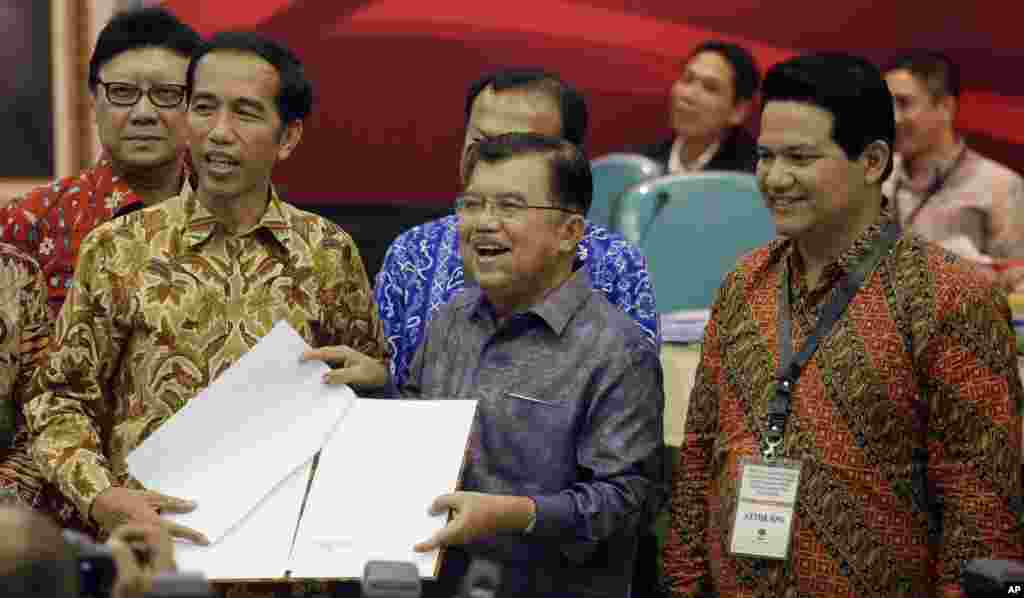 Presiden Indonesia terpilih Joko "Jokowi" Widodo dan Wakil Presiden terpilih Jusuf Kalla menerima dokumen keputusan Komisi Pemilihan Umum (KPU) dari Ketua KPU Husni Kamil (kanan) di Kantor KPU (22/7). (AP/Achmad Ibrahim)