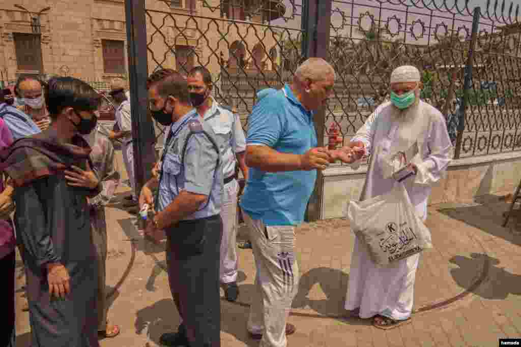 A man distributes prayer rugs and masks outside Al-Azhar Mosque in Cairo, Aug. 28, 2020. (Hamada Elrasam/VOA)