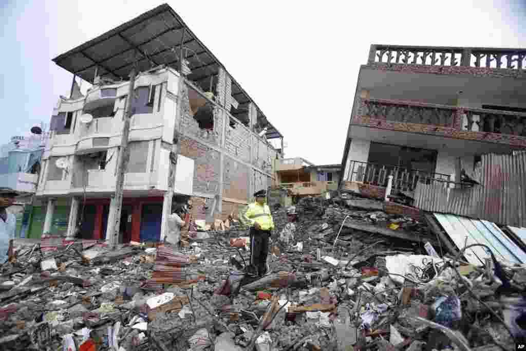 A police officer stands on debris, next to buildings destroyed by an earthquake in Pedernales, Ecuador, April 17, 2016. The earthquake flattened buildings and buckled highways along its Pacific coast, sending the Andean nation into a state of emergency.