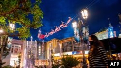 Une femme portant un masque facial se promène devant les décorations de Noël au centre commercial en plein air The Grove, à Los Angeles, aux Etats-Unis, le 5 novembre 2020. (Photo par VALERIE MACON / AFP)