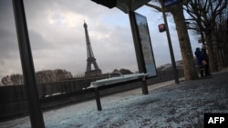 Un autobús dañado detenido en París y al fondo la torre Eiffel, un día después de protestas de los "chalecos amarillos", en el cuarto fin de semana de disturbios. Domingo, 9 de diciembre de 2018. 