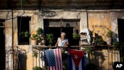 Dalam foto tertanggal 19/12/2014 ini, seorang warga Kuba Javier Yanez berdiri di balkoni rumahnya di Havana, dimana ia menggantungkan bendera Amerika dan Kuba setelah mendengar berita pencairan hubungan AS- Kuba. 