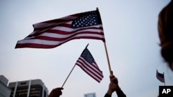Crowd members wave American flags during a vigil downtown for the victims of a mass shooting at the Pulse nightclub Monday, June 13, 2016, in Orlando, Fla.(AP Photo/David Goldman)