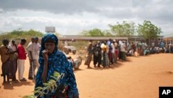 A Somali woman stands in front of Somalis queuing outside the reception center in Ifo refugee camp, one of three camps in Kenya's Dadaab refugee complex on July 25, 2011