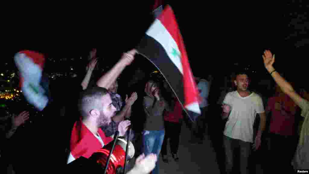 Pro-Assad demonstrators wave flags and shout slogans at Mount Qasioun, Damascus, Sept. 1, 2013.