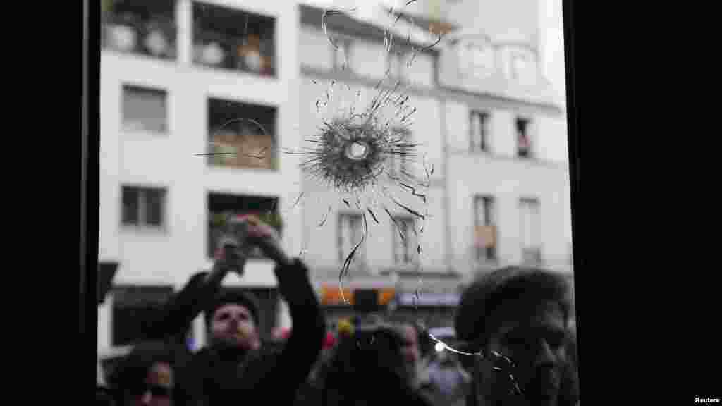 Journalists work outside a restaurant where bullet impacts are seen the day after a series of deadly attacks in Paris, France, Nov. 14, 2015.