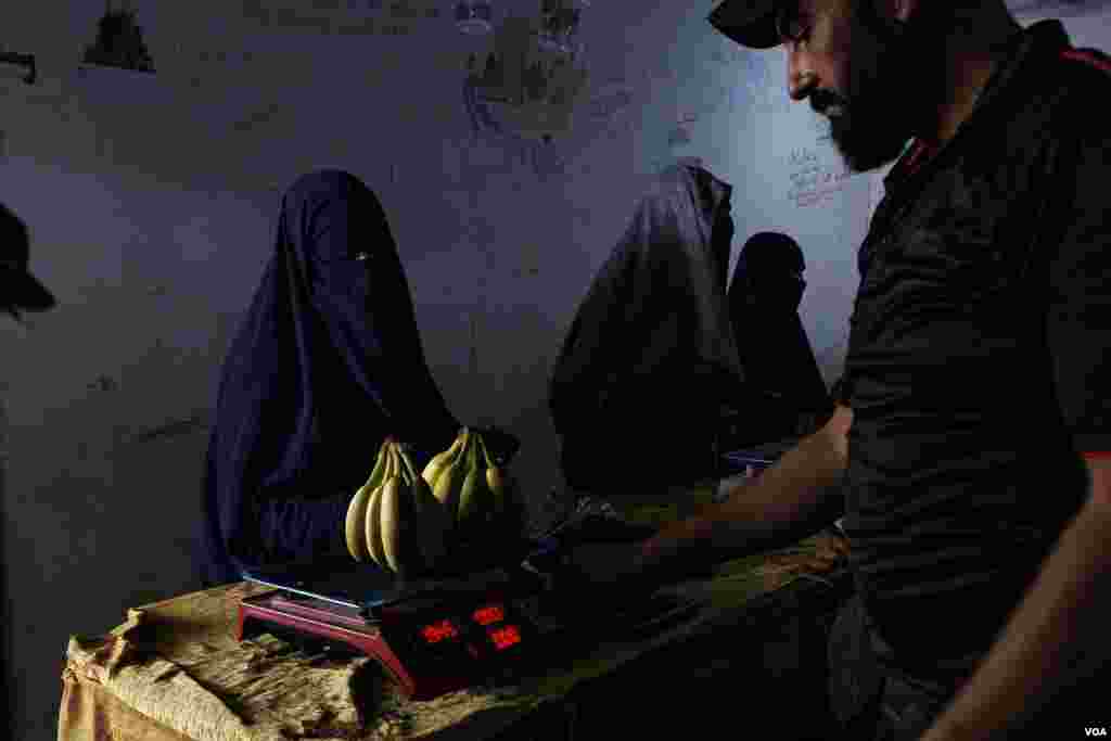 A female prisoner buys fruits in the market area of Roj Camp where most of the western women kept in northeastern Syria have been relocated to the last years, on Oct. 13, 2024 (Diego Baravelli/VOA)