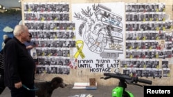 People walk next to a graffiti supporting the release of all hostages who have been held in Gaza since the deadly October 7, 2023 attack, in Tel Aviv