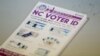 FILE - A pile of government pamphlets explaining North Carolina's controversial "Voter ID" law sits on table at a polling station, July 15, 2016.
