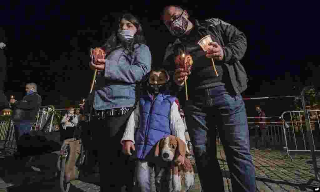 Una familia con máscaras protectoras posa para una foto mientras asisten a la misa de la Pascua Ortodoxa a medianoche frente a la catedral Alexander Nevsky en Sofía, Bulgaria, el domingo 19 de abril de 2020.