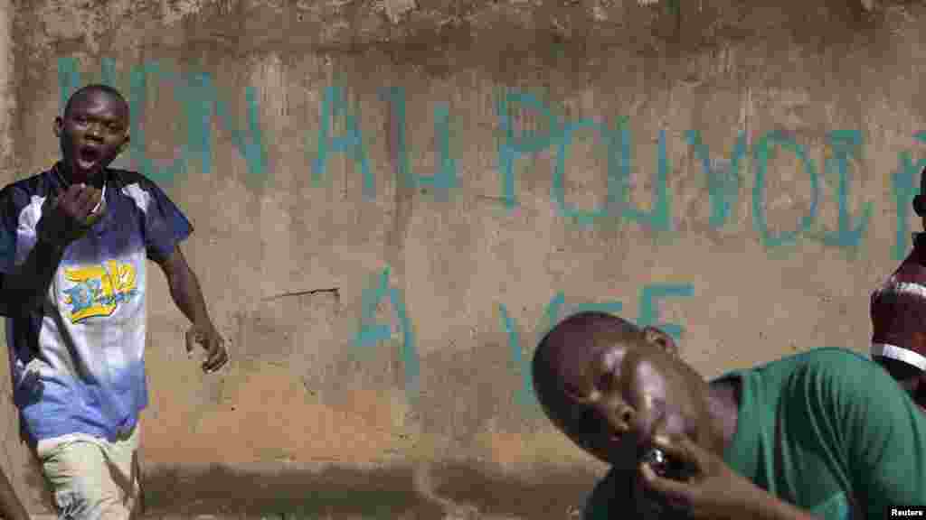 Les manifestants marchent devant des graffitis avec la mention "Non au pouvoir à vie", en référence au président Blaise Compaoré, à Ouagadougou, au Burkina Faso, le 28 Octobre 2014. La police a tiré des gaz lacrymogènes sur les manifestants qui ont usé des pierres.