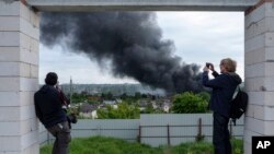 Periodistas extranjeros reportan desde un punto de observación, cerca de una columna de humo tras un ataque ruso, en Járkiv, Ucrania, el 17 de mayo de 2024.