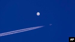 Sebuah jet tempur terbang di dekat balon besar yang melayang di atas Samudra Atlantik, tepat di lepas pantai Carolina Selatan dekat Pantai Myrtle, Sabtu, 4 Februari 2023. (Foto: via AP)